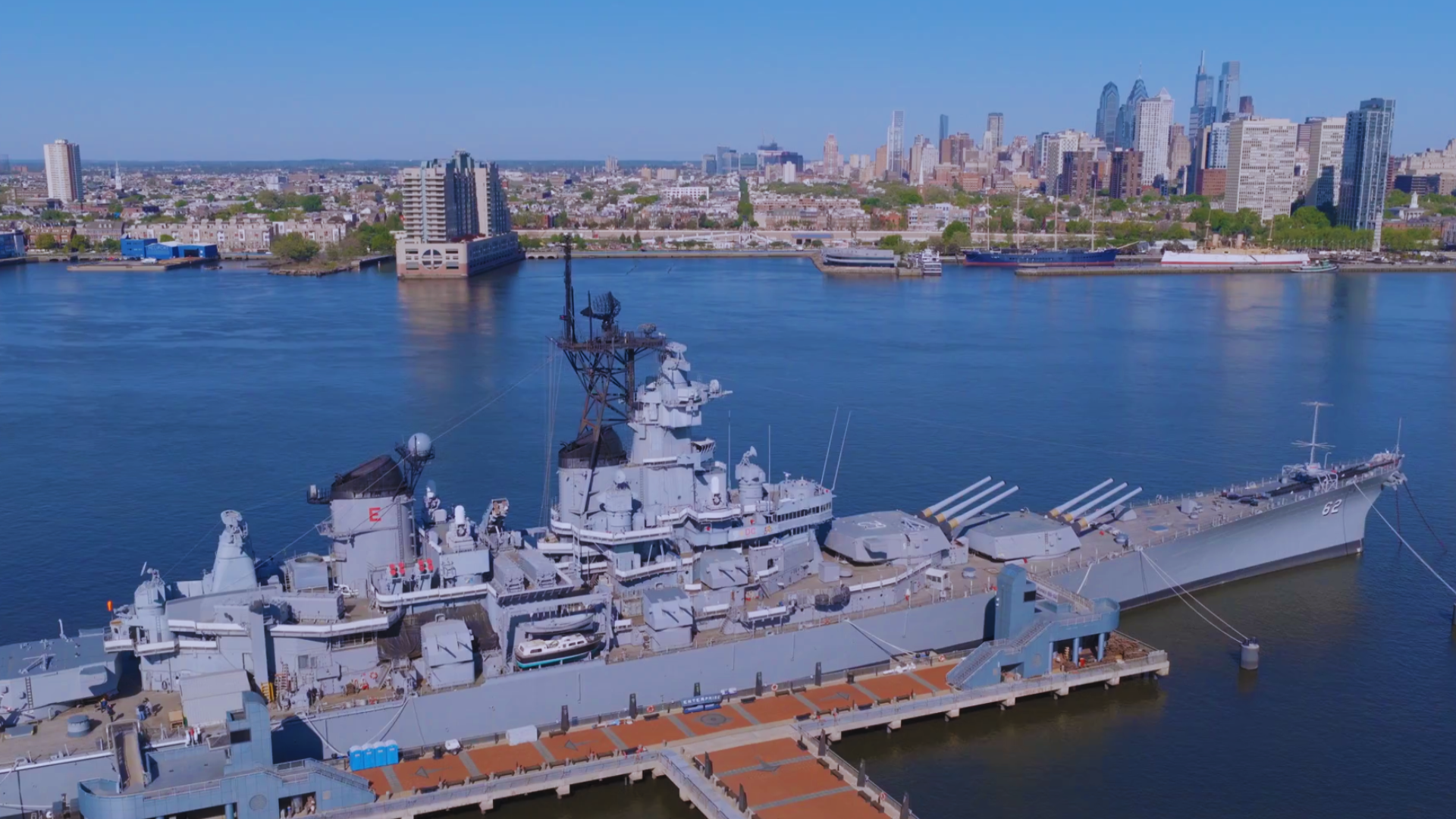 Decommissioned battleship moored beside a city skyline, representing state-built national power and strategic infrastructure